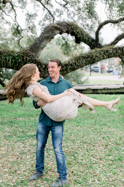man cradling woman in his arms by a Florida live oak tree, both laughing