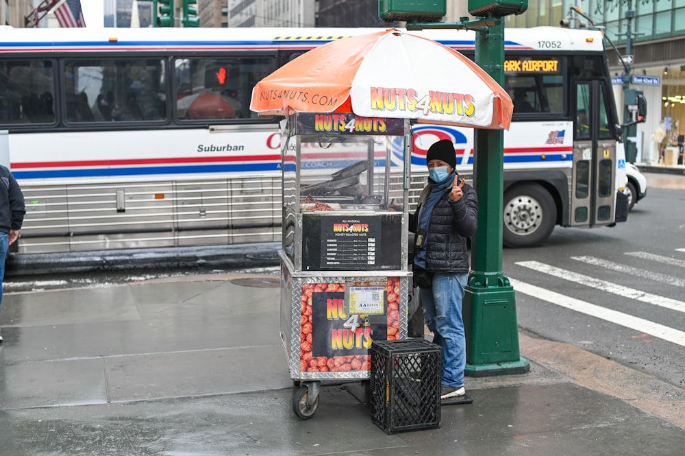 man in green jacket and black pants standing beside shopping cart