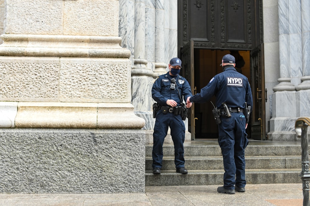 Hombre con chaqueta negra y jeans de mezclilla azul de pie en escaleras de concreto gris