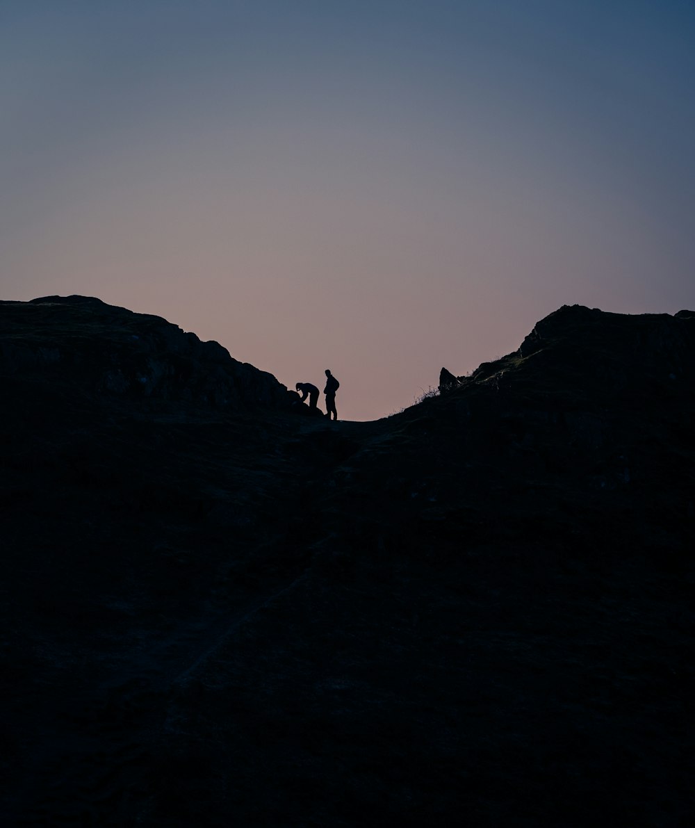 silhouette of 2 people on top of mountain