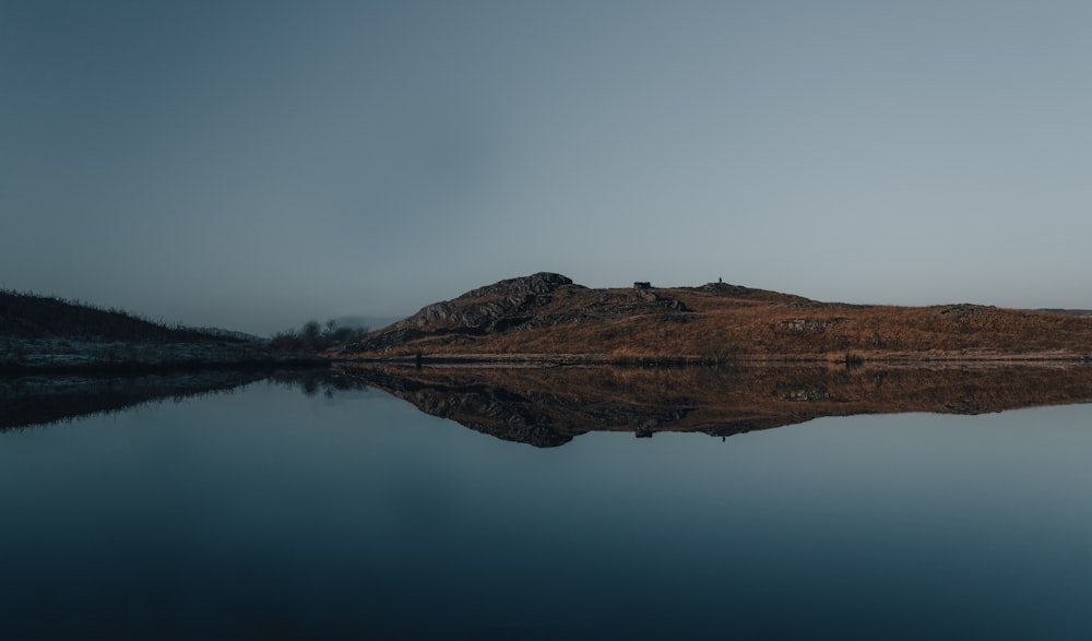 brown mountain beside body of water