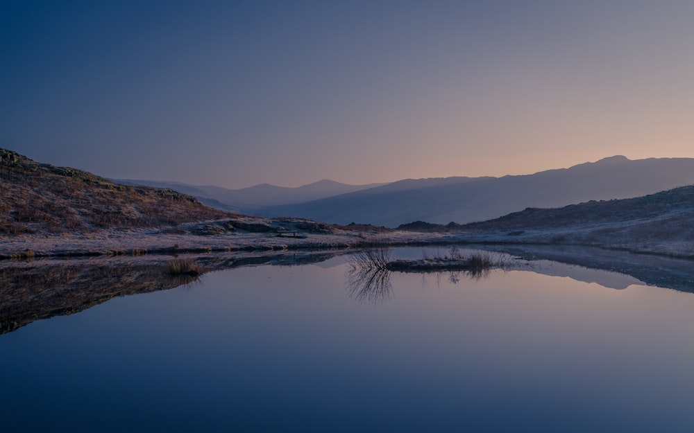 body of water near mountain during daytime