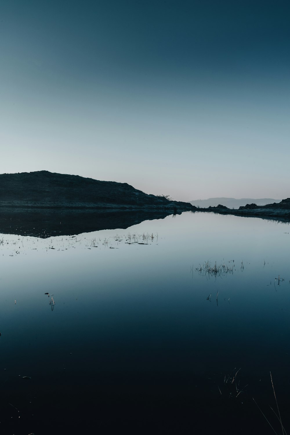 昼間の青空の下、山の近くの湖