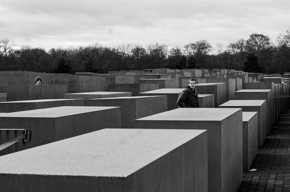 grayscale photo of man sitting on concrete bench