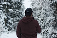 person in red hoodie and black cap standing on snow covered ground