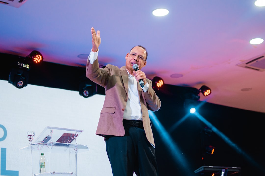 man in white dress shirt and black pants singing on stage