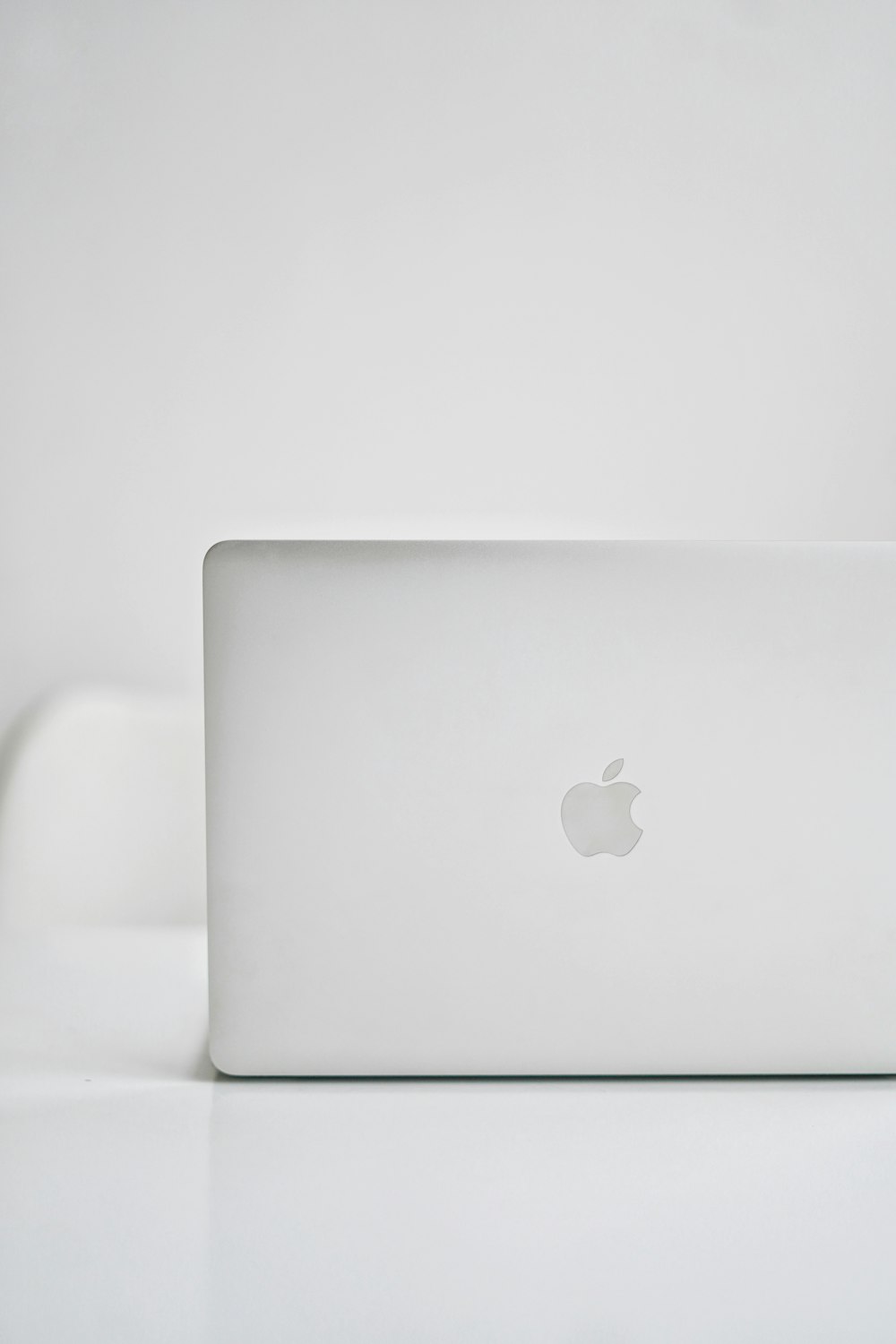 silver macbook on white table