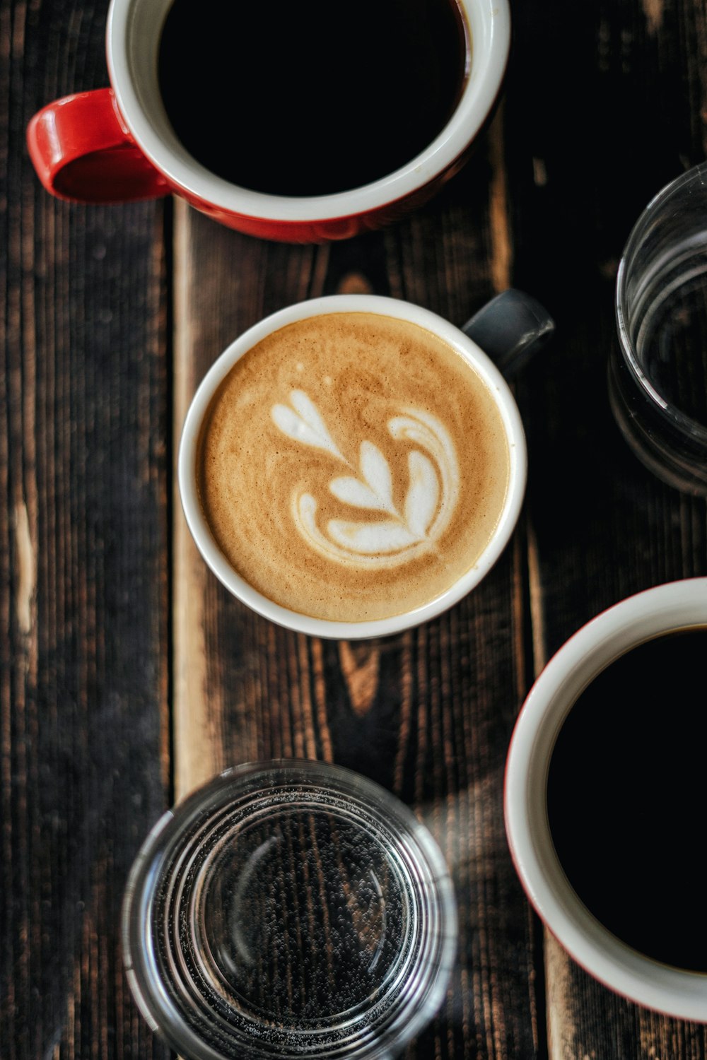 Cappuccino en taza de cerámica blanca sobre mesa de madera marrón