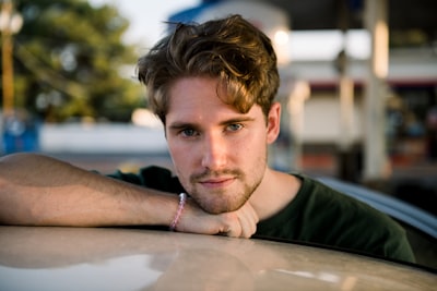 man in black crew neck shirt leaning on brown wooden table handsome google meet background