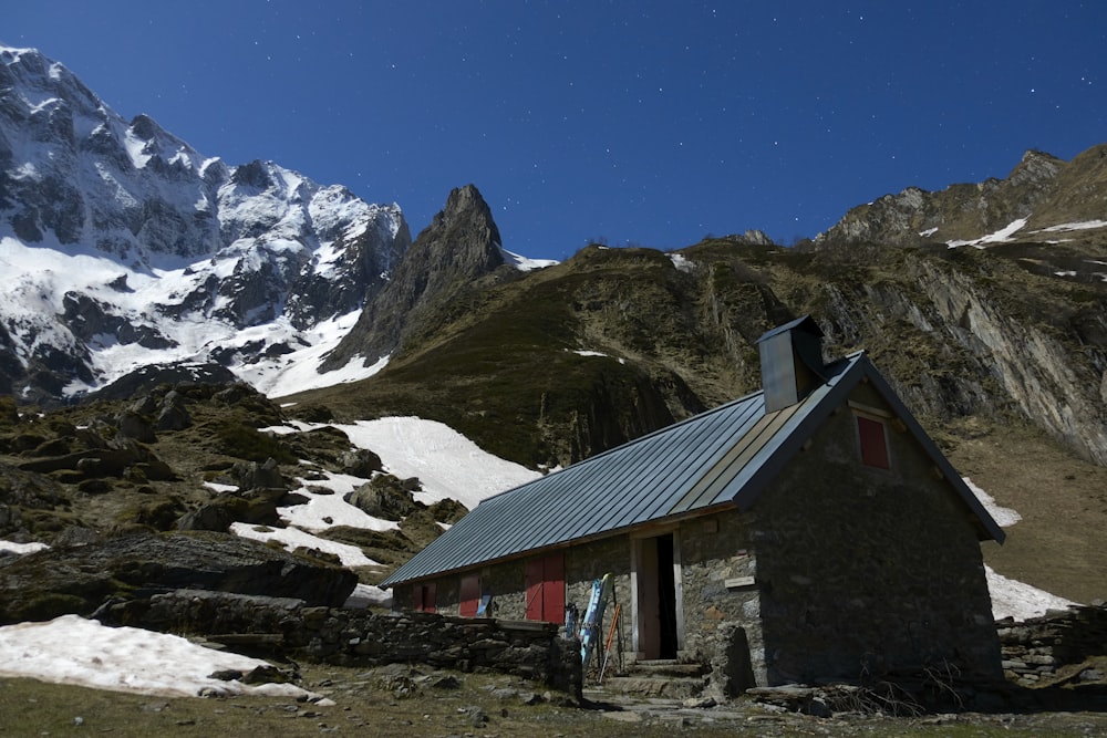 brown wooden house near snow covered mountain during daytime