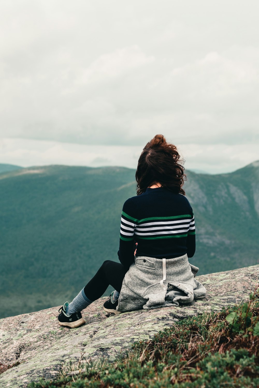 woman in black and white striped long sleeve shirt sitting on rock