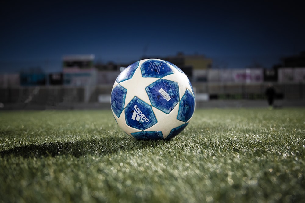 Ballon de football bleu blanc sur un terrain en herbe verte pendant la journée