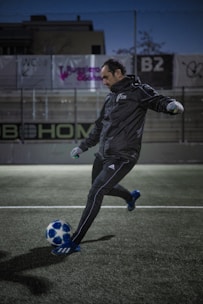 Action shot of a soccer creator filming a freestyle trick on a neon-lit urban pitch.