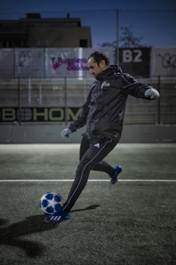 A close-up shot of a soccer boot striking a ball on a textured pitch under stadium lights.