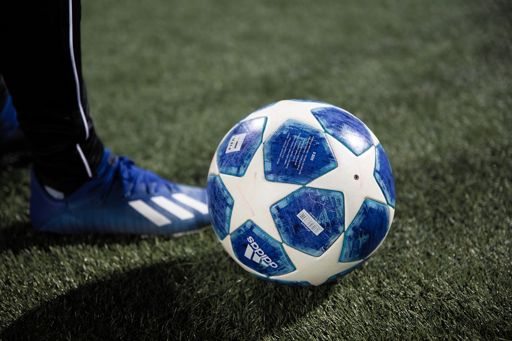 bola de futebol azul e branca no campo de grama verde