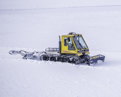 yellow and black tractor on snow covered ground during daytime