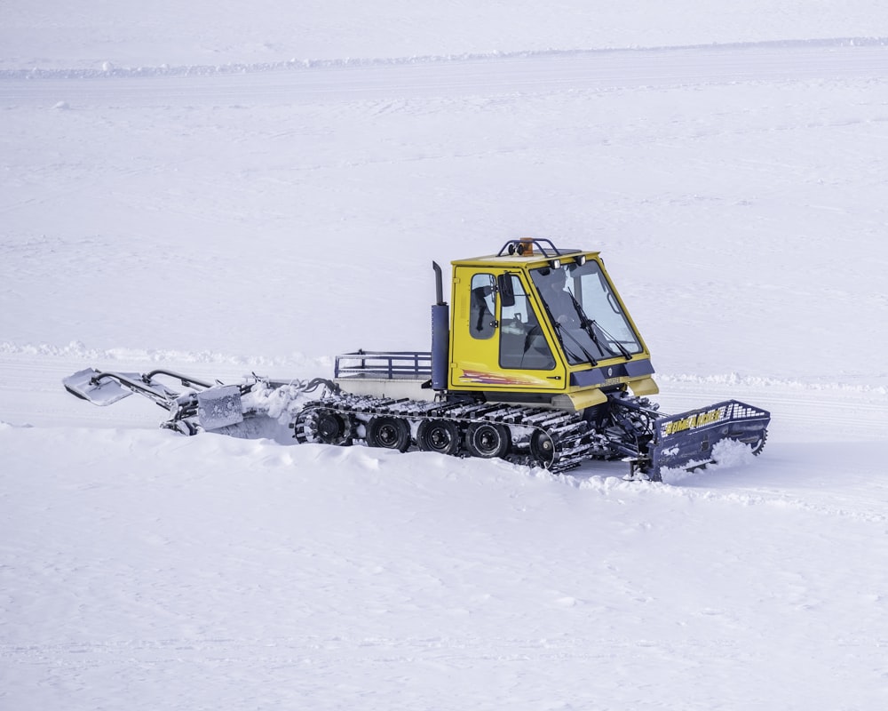 yellow and black tractor on snow covered ground during daytime