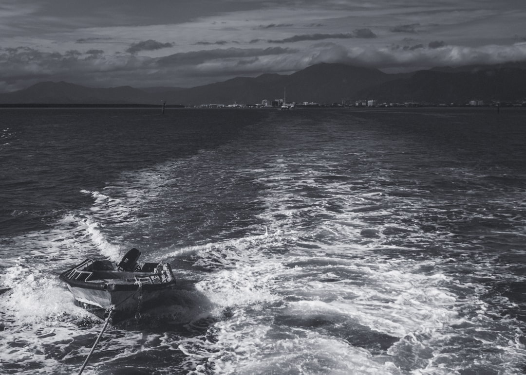 grayscale photo of man riding on boat on sea