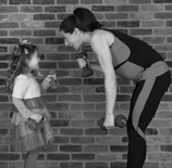 A cheerful mom and toddler stretching together in a bright pink workout room.