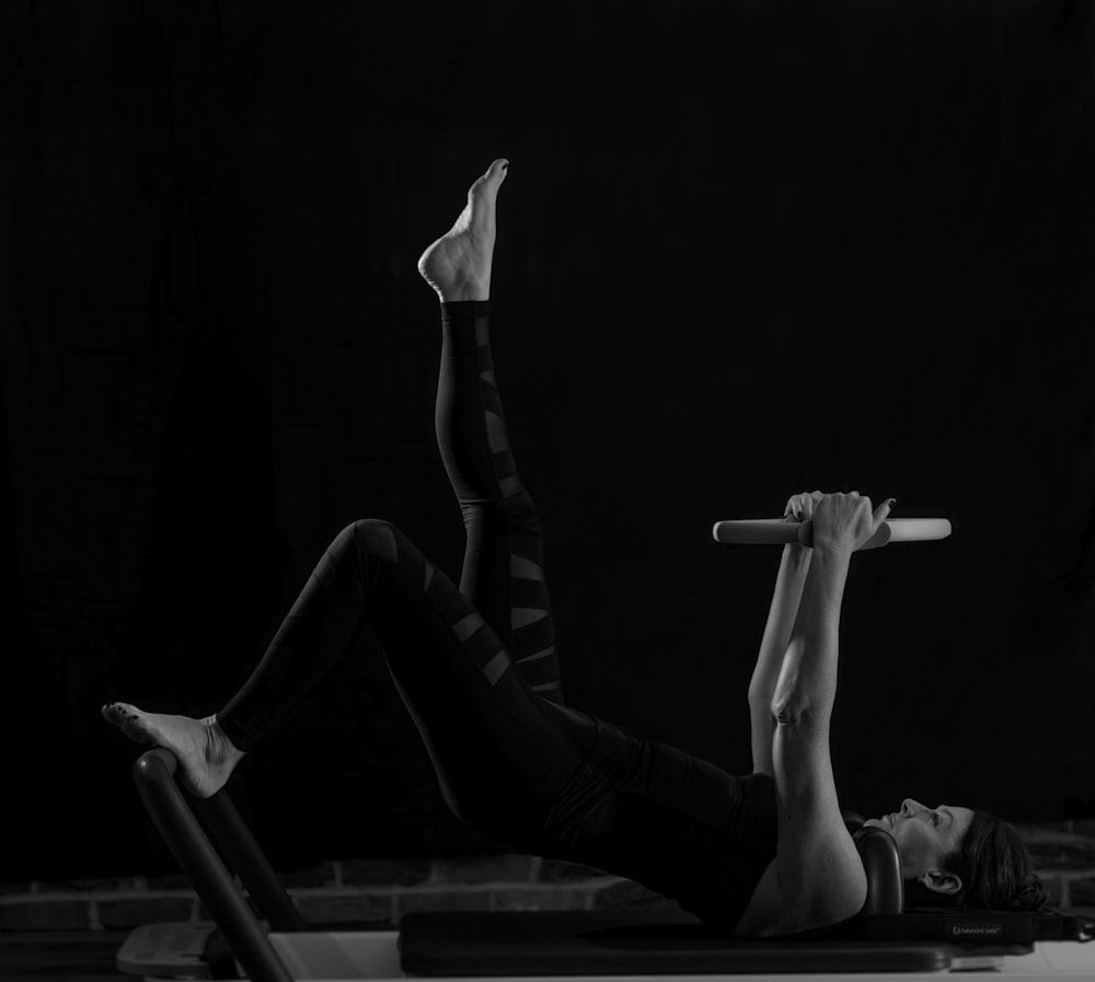 woman in black pants and black boots lying on black wooden bench