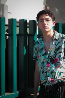 Model wearing a bright shm regatta polo shirt leaning casually against a wooden fence.