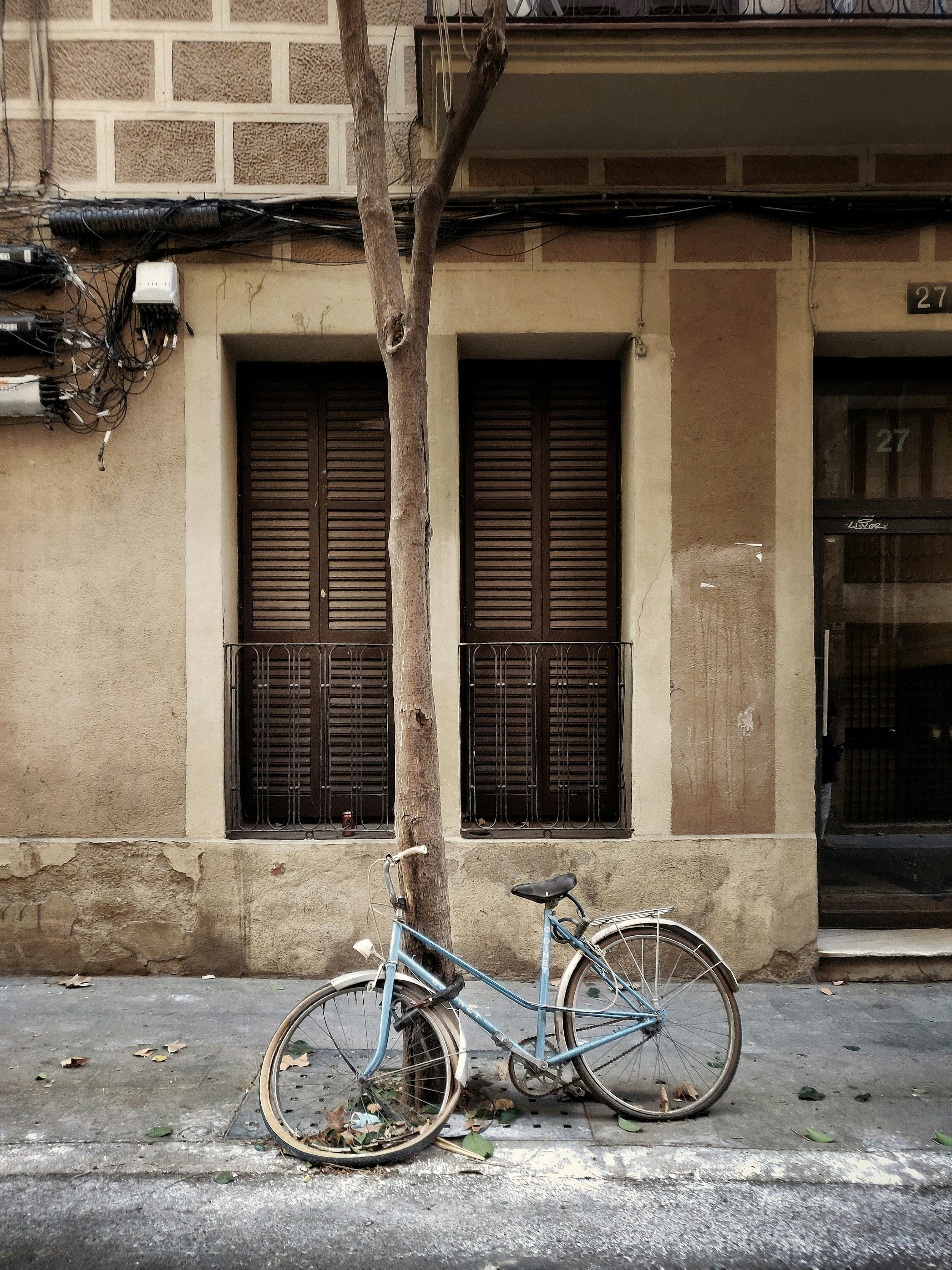 blue city bike parked beside brown concrete building during daytime