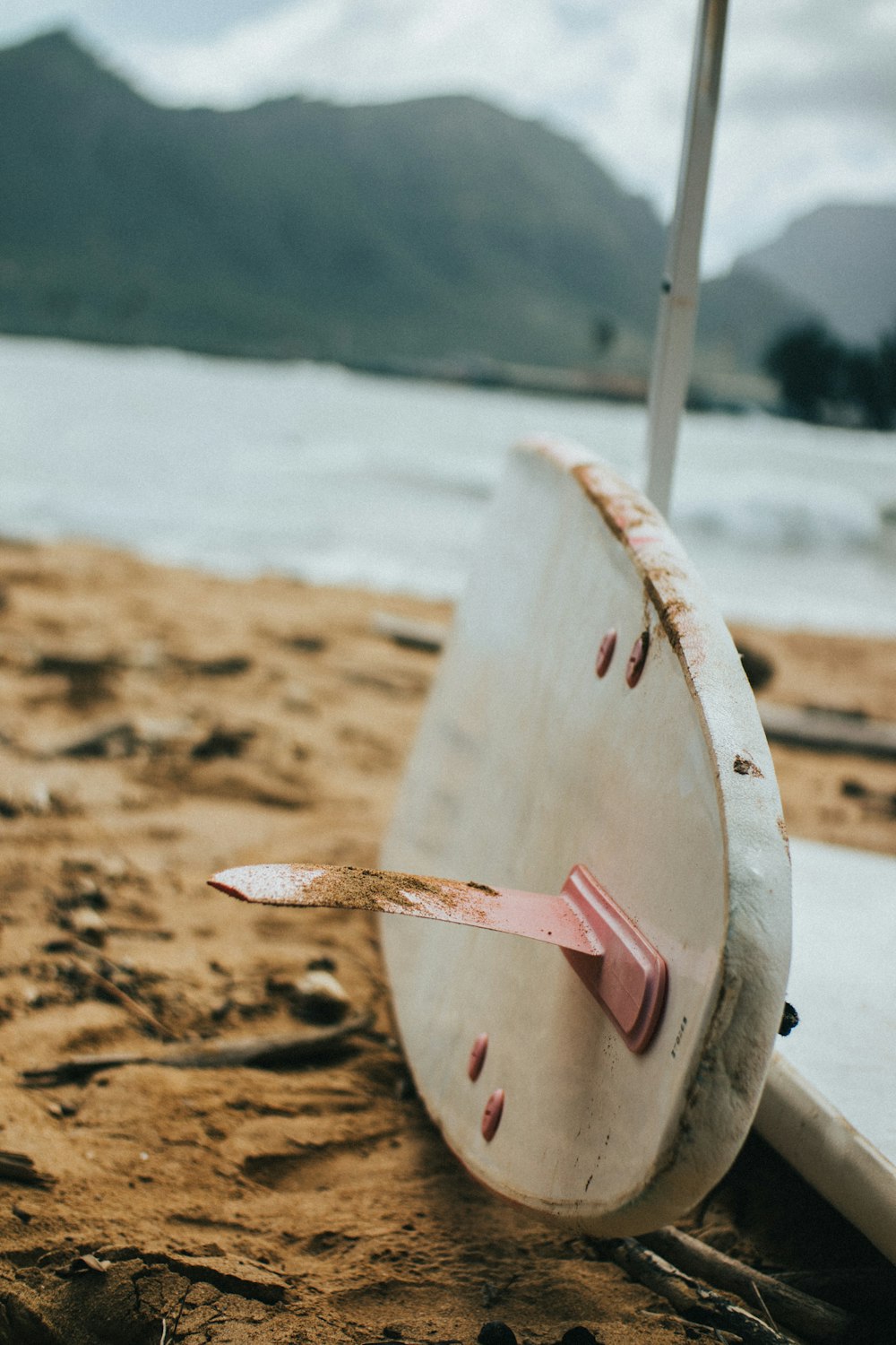 prancha de surf branca na areia marrom perto do corpo de água durante o dia