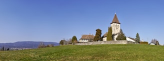 brown and white concrete house near green grass field under blue sky during daytime