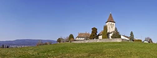 brown and white concrete house near green grass field under blue sky during daytime