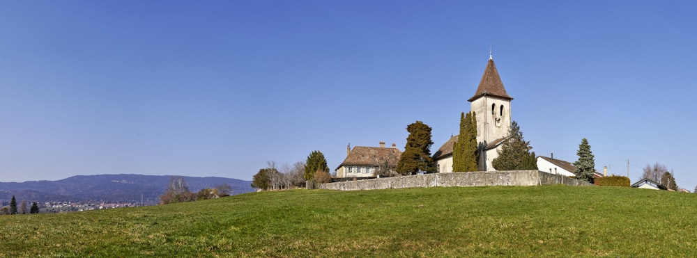 Casa de concreto marrón y blanco cerca de campo de hierba verde bajo cielo azul durante el día