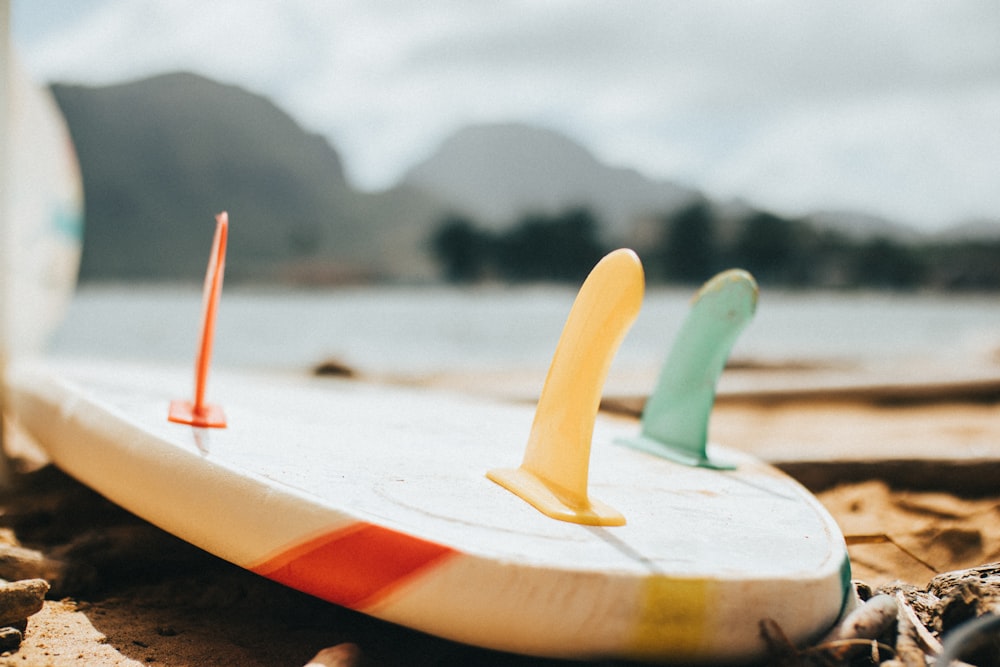 white and red surfboard on beach shore during daytime