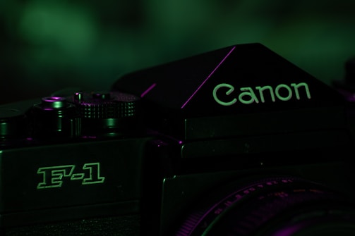 A close-up of a vintage camera focusing on the logo and model, with a dark, moody lighting that incorporates green tones.