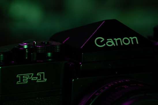 A moody, cinematic shot of a vintage film camera against a dark, textured backdrop with green and gray tones.
