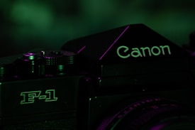 A close-up of a vintage camera focusing on the logo and model, with a dark, moody lighting that incorporates green tones.