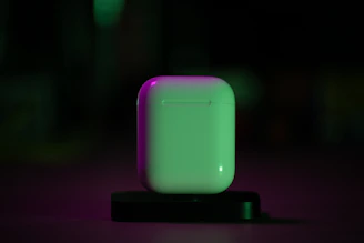 AirPods case glowing softly against a matte black surface with yellow highlights
