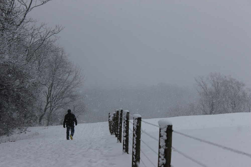 person in black jacket walking on snow covered field during daytime