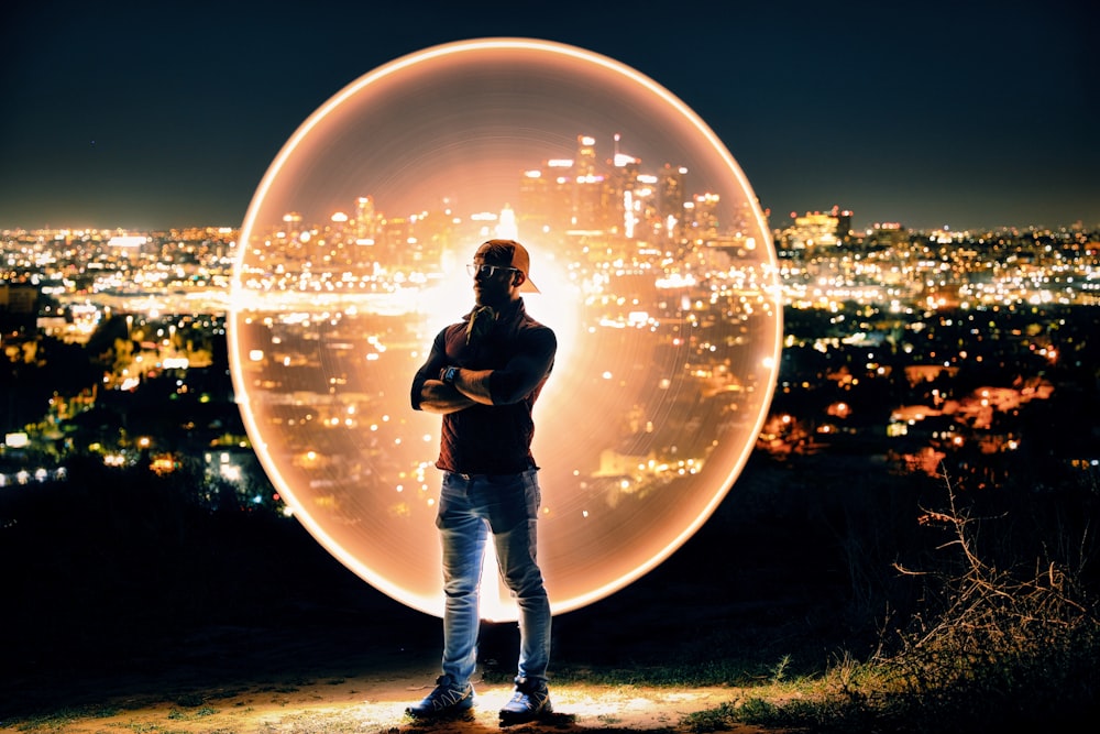 man in black jacket and blue denim jeans standing on ground during night time