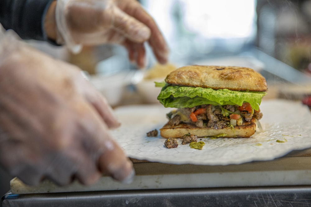 person slicing burger on white table