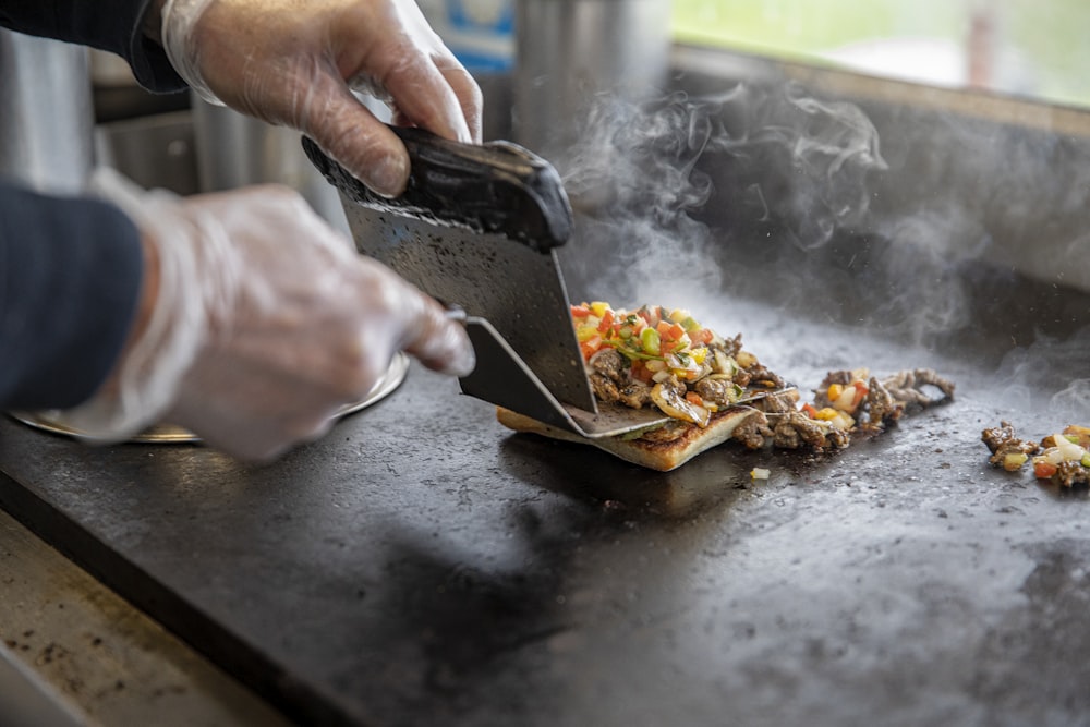 person holding black knife slicing food