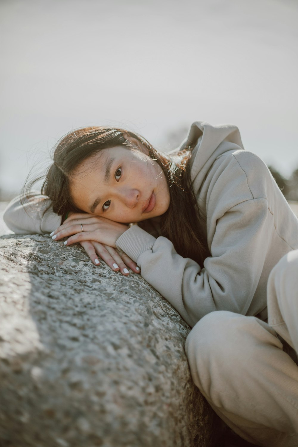 girl in white long sleeve shirt lying on gray rock