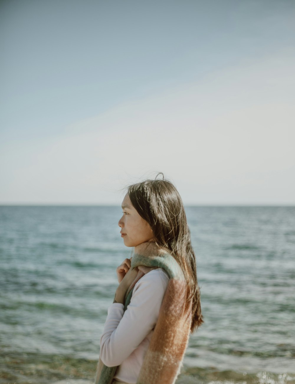 woman in white long sleeve shirt standing near body of water during daytime