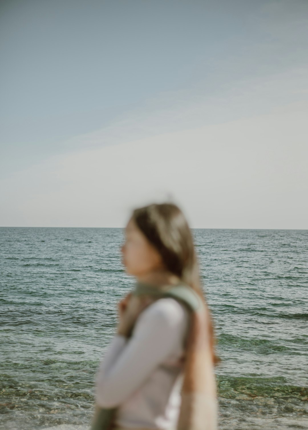 woman in white tank top standing on sea shore during daytime