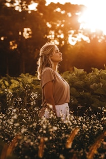 woman in brown tank top standing on green grass field during sunset