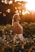 woman in brown tank top standing on green grass field during sunset