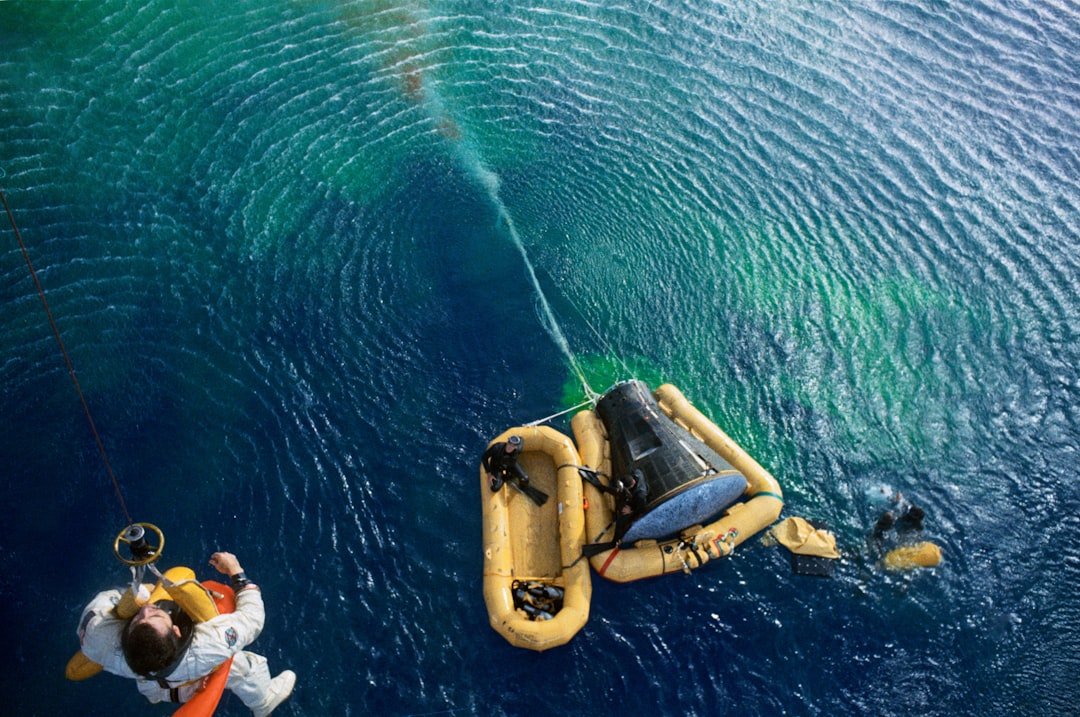 Astronaut is lifted out of his landing craft over the water