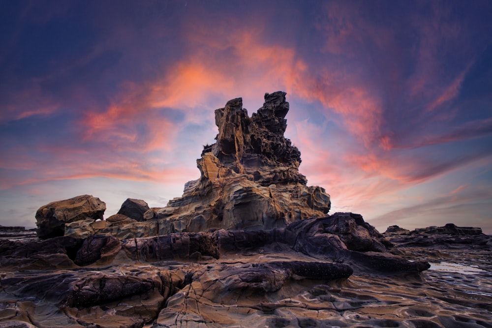 brown rock formation under orange and blue sky