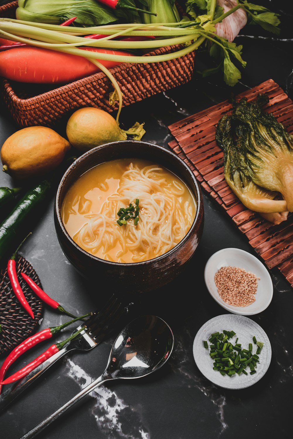 noodle soup on black ceramic bowl beside yellow fruit