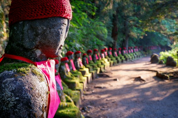 Man in red knit cap and green shirt standing on brown dirt road during daytime — Nikko, Japan