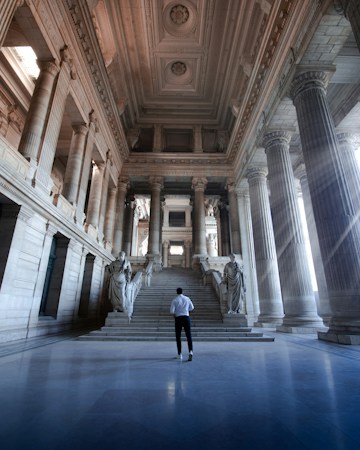 Two people walking down a long institutional hallway, similar to the corridors outside a busy housing courtroom