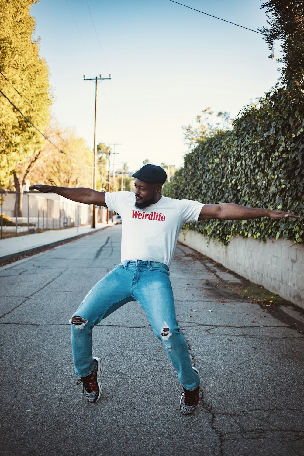 Donna in t-shirt girocollo bianca e jeans in denim blu che salta sulla strada di cemento grigia